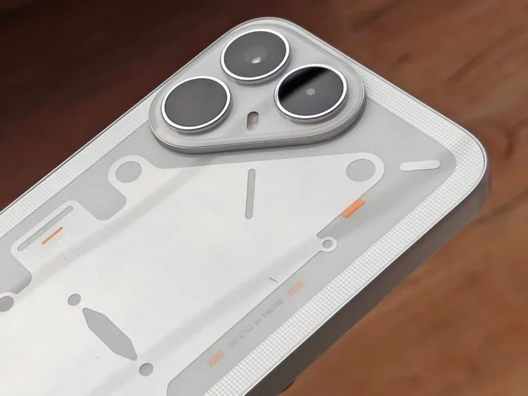 Tecno Pova 8 5G rear close-up, semi-transparent white back with blueprint-style lines, triple camera setup with silver rings, orange accent details, textured edge grip