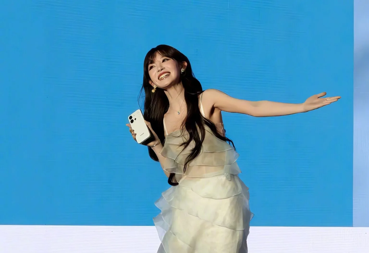 Vivo S60 Vitality Edition: AMOLED Display, Dimensity 7500 and 7,200mAh Battery Chinese actress Tian Xiwei smiling and holding the white Vivo S60 Vitality Edition smartphone at a launch event, against a bright blue background