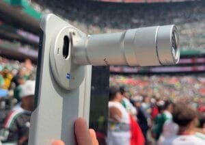 Vivo X Fold 6 foldable smartphone with extended telephoto lens accessory, ZEISS certified camera system, light textured rear panel, captured at stadium event for long distance shooting.