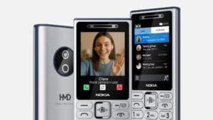 Official promotional shot of the new 2026 HMD Nokia feature phones. Three devices are displayed: the rear view shows the silver HMD model with dual camera lenses and "HMD Makers of Nokia phones" branding; the front view displays the dedicated AI button below the screen, with one unit showing an active video call interface and another showing the Xpress Chat messaging app, all set against a clean light gray background.