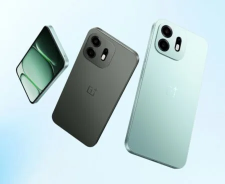 Three views of the OnePlus N6 smartphone against a soft light blue background: one showing the front display, and two showing the rear design in Dark Gray and Fresh Mint colors. The back features a rectangular camera module with two lenses, an LED flash, and the OnePlus logo centered below.