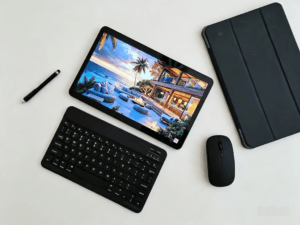 Tecno Mega PAD 2 laid flat on a plain white surface, paired with a matching Bluetooth keyboard, protective case, wireless mouse, and stylus pen. The tablet displays a vivid scenic wallpaper, highlighting its sleek design and full accessory bundle.