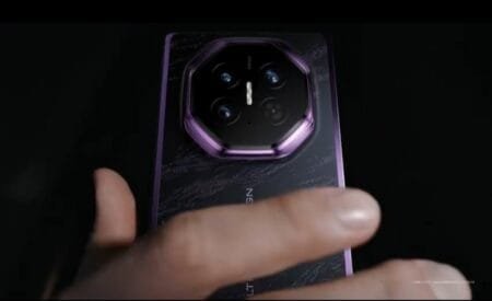 Huawei Teases Mate XT 2 With Three New Color Options Close-up view of Huawei Mate XT2 Extraordinary Edition in Brocade Purple finish, showing octagonal camera module with purple metallic frame, textured black back panel, and hand holding the device.
