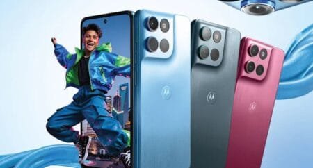 Promotional banner for the Motorola Moto G Max showing three rear panels in Blue, Gray, and Pink satin finishes with square camera modules and Motorola logo, alongside the front display with punch-hole camera. Colorful design set against a light blue backdrop with flowing fabric accents.