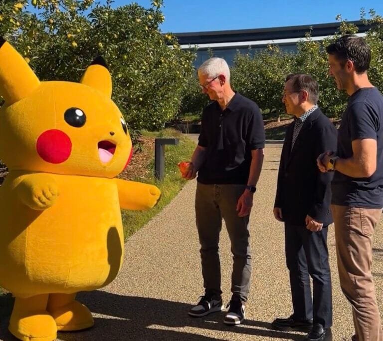 Tim Cook offers an apple to Pikachu alongside The Pokémon Company CEO Tsunekazu Ishihara and John Ternus at Apple Park campus