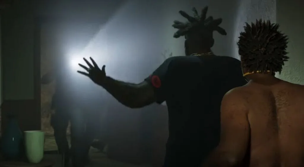 GTA 6 Extended Look Released: Everything Shown in the 27-Minute Video 1 GTA 6 Extended Look gameplay scene showing two characters viewed from behind inside a dimly lit room, one holding up a hand toward a bright flashlight beam in the doorway, Leonida criminal mission gameplay.