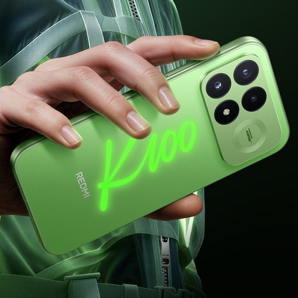 Redmi K100 Pro Glowing Firefly Variant Unveiled 1 A close-up shot of a hand holding the Redmi K100 Pro, demonstrating its glow-in-the-dark feature. A bright, glowing green "K100" logo is hand-drawn across the translucent green rear panel, which also features a square camera island with four circular cutouts and a "Sound by Bose" branding badge.