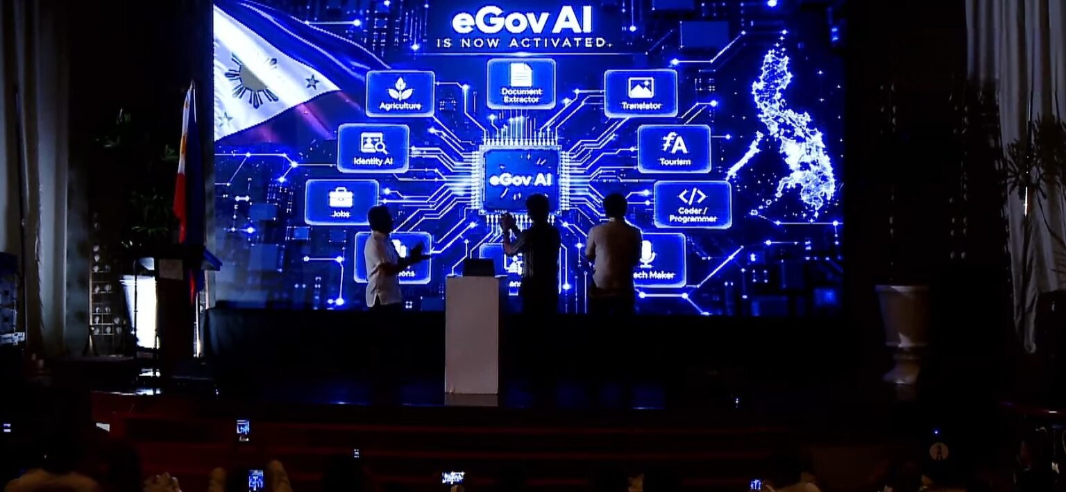 DICT Adds Free AI Assistant to eGovPH App, Now Serving 61 Million Filipinos eGovAI launch event at The Manila Hotel, large digital screen displaying features including Identity AI and Document Extractor, Philippine flag on left, three silhouettes on stage