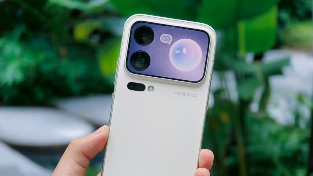 Xiaomi 18 Pro Max Launched in China with Snapdragon 8 Elite Extreme Gen 6, Dual 200MP Cameras and 8,500mAh Battery Xiaomi 18 Pro Max white rear view, secondary display showing "Hi~" message, dual camera lenses, Leica branding, held against green foliage background