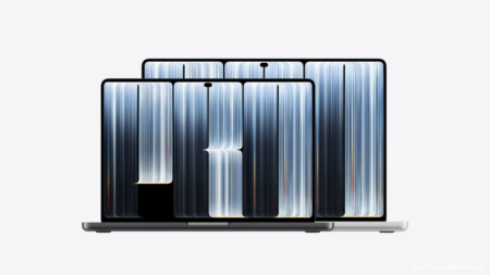Two Apple MacBook Pro 2026 units in space‑gray and silver finishes, showing their PROLED XRD displays with flowing blue‑white line‑art graphics, set against a plain light‑white background.